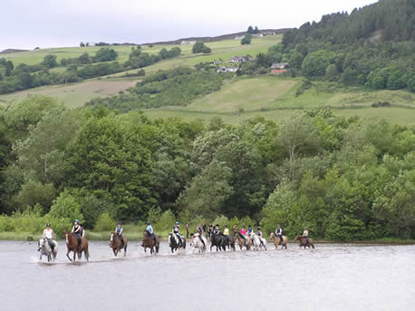 Student riding through loch on horses